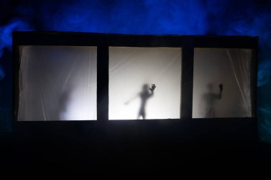 Sanat dekorasyonu. İçinde büyük pencereler ve zombiler olan eski bir ev. Penceredeki bulanık korkunç siluetler. Korku Cadılar Bayramı konsepti