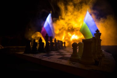 Rusya ve Ukrayna arasındaki savaş, satranç tahtası, askerler ve patlamanın arka planındaki ulusal bayrakları kullanarak savaşın kavramsal görüntüsü. Ukrayna ve Rusya krizi. Seçici odak