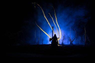 Karanlık sisli ormanda tırpanla ölüm. Ormanda Azrail 'i tutan kadın hayalet, cadılar bayramı konsepti. Seçici odak içindeki yaratıcı sanat tablosu dekorasyonları