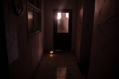 Cadılar Bayramı konsepti Karanlık koridorda balkabağı kafalı ürkütücü bir siluet. Arka planda sis olan tonlu bir ışık. Seçici odaklanma. Uzun deklanşör.
