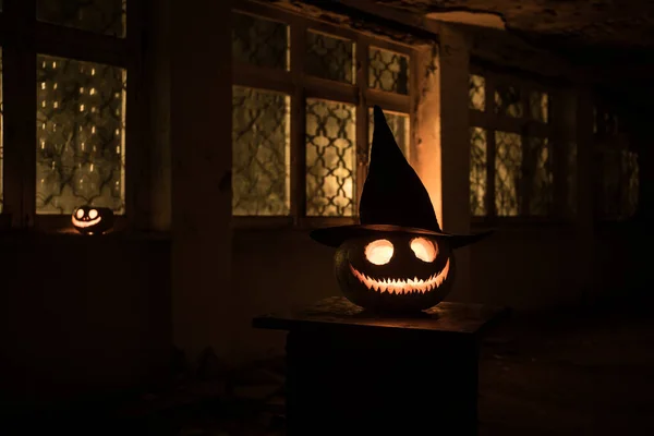 Scary Halloween pumpkin in the mystical house window at night or halloween pumpkin in night on abandoned room with window. Selective focus