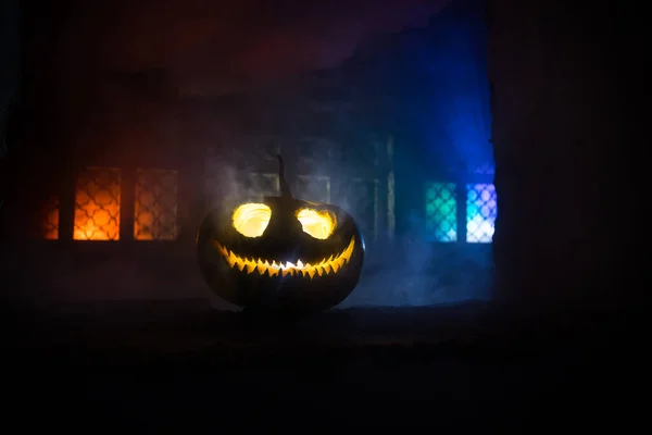 Scary Halloween pumpkin in the mystical house window at night or halloween pumpkin in night on abandoned room with window. Selective focus