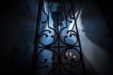 Korku Cadılar Bayramı konsepti. Ürkütücü terk edilmiş kale. Eski bir şamdan ve Cadılar Bayramı balkabağı geceleri tahta merdivenlerde parlıyor. Merdivenlerdeki insan silueti. Seçici odak