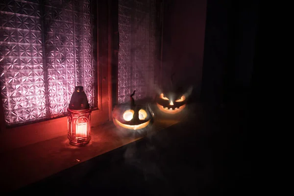 Scary Halloween pumpkin in the mystical house window at night or halloween pumpkin in night on abandoned room with window. Selective focus