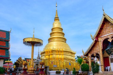 Beautiful view of Hariphunchai pagoda and surrounding chapels with blue sky and white cloud as background. This place is located in Lamphun province in the northern of Thailand. Complementary color.