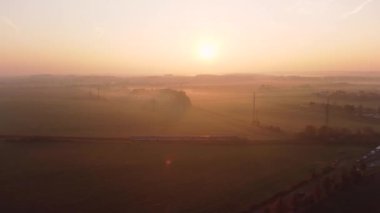 Tren sonbahar gündoğumunda kırsal kırsalda yol alır. Tren doğadaki güzel sonbahar tarlası boyunca yol alır..