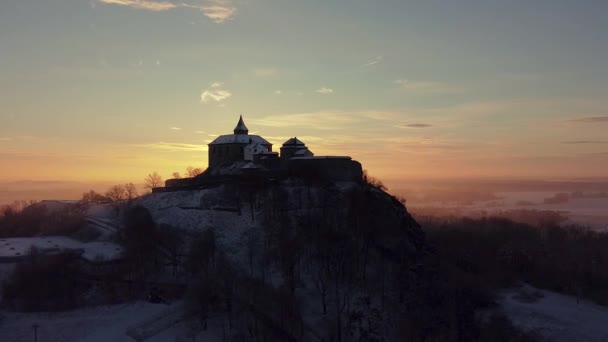 Vista aérea e matinal do castelo em pé na colina acima do nevoeiro ao nascer do sol, luz pelos raios de sol matinais. — Vídeo de Stock