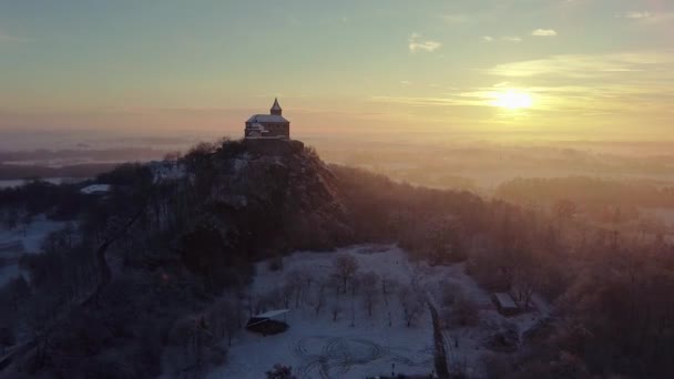 清晨空中俯瞰城堡的景象，日出时分，城堡矗立在山顶上的雾气之上，晨曦照亮了它. — 图库视频影像