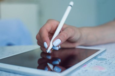 Genç kadınlar el ele tutuşup tablet ekranda dijital kalem kullanıyorlar..