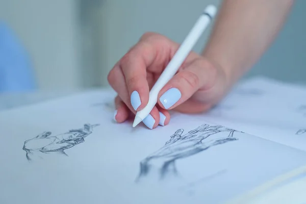 Frau hält digitalen Stift in der Hand und zeigt auf Bleistiftskizzen im Buch. — Stockfoto