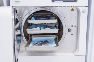 Diş hekimliği kliniğinde paketlenmiş diş aletleriyle modern laboratuvar otoklavisi. Dezenfeksiyon ve sterilizasyon için modern tıbbi ekipmanlar.