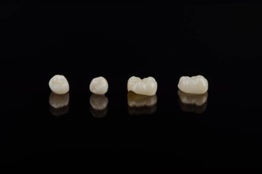 Nitelikli anatomik seramik ve zirkon insan dişlerinden taçlar siyah arkaplanda izole edilmiş makroyu kapatın.