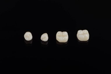 Nitelikli anatomik seramik ve zirkon insan dişlerinden taçlar siyah arkaplanda izole edilmiş makroyu kapatın.