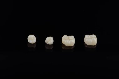 Nitelikli anatomik seramik ve zirkon insan dişlerinden taçlar siyah arkaplanda izole edilmiş makroyu kapatın.