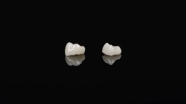 Nitelikli anatomik seramik ve zirkon insan dişlerinden taçlar siyah arkaplanda izole edilmiş makroyu kapatın.