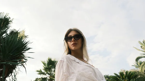 Business woman looks straight forward to camera from top through black sunglasses