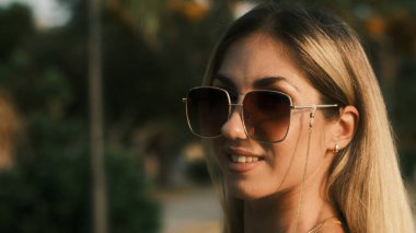 Smiling girl in sunglasses posing at camera on the nature
