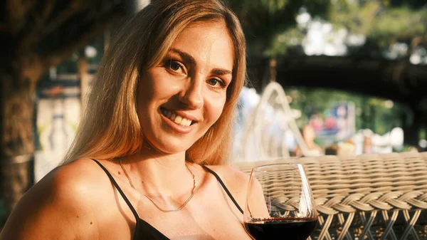 Lady drinking red wine and smiling at camera