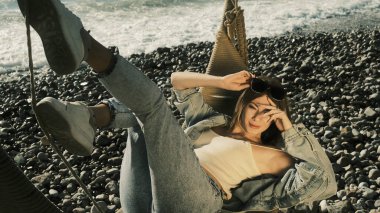 Kız kameraya poz vererek salıncakta yatıyor.