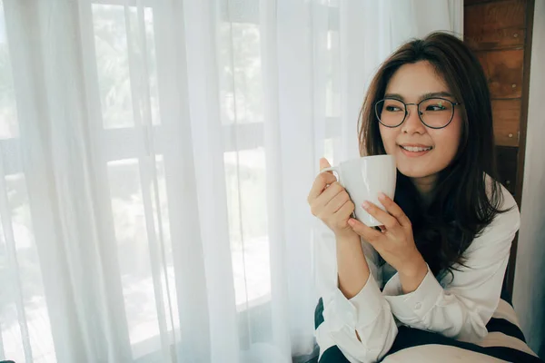 Gyönyörű Fiatal Ázsiai Ablaknál Mosolyog Egy Csésze Kávét Tart Kezében — Stock Fotó