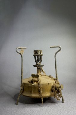 Gri bir arka planda toz ve örümcek ağlarında eski gazyağı primusu