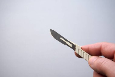 Açık gri arka planda tek kullanımlık cerrahi neşter.