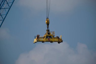 Mavi gökyüzü arka planına sahip endüstriyel vinç otomatik olarak havada asılı.
