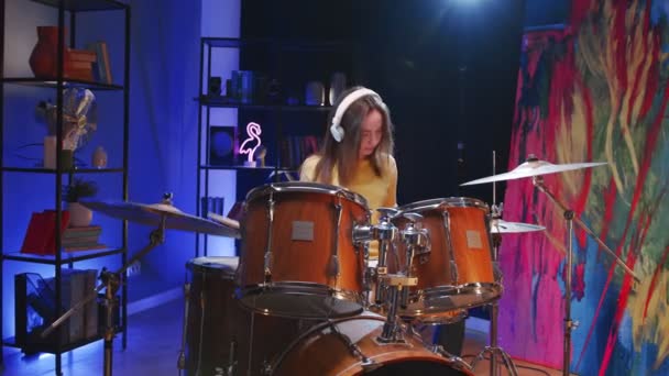 ヘッドフォンを装着した女性ミュージシャンの腰を上げるポートレートは、コンサートの準備中にドラムを演奏します。音楽と趣味のコンセプト — ストック動画