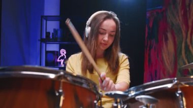 Kafkasyalı genç bir kadının kulaklık taktığı ve garaj stüdyosunda davul çalmaktan zevk aldığı görüntüler. Müzik konsepti