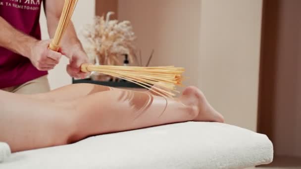 Concetto di relax e cura del corpo. Ritratto ravvicinato di giovane donna sdraiata sul divano da massaggio mentre il terapeuta la massaggia con strumenti speciali nel salone di bellezza — Video Stock