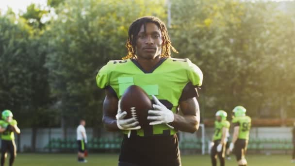 Portrait of multiracial male American football player holding a ball while standing at the stadium. Sport and games concept — Stock Video