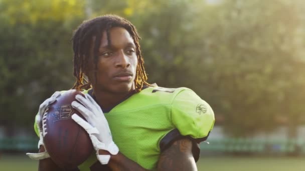 Portret van een zelfverzekerde professionele multiraciale Amerikaanse voetballer zonder helm in uniform gooien de bal op het veld tijdens het spel of training. Extreem sportconcept — Stockvideo