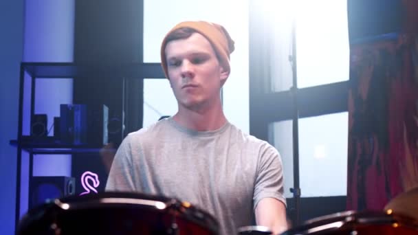 Midja upp porträttvy över den unge mannen som spelar på trummor medan han tillbringar tid i rummet med neonljus. Musikkoncept — Stockvideo