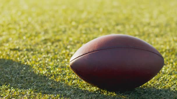 Oříznutý pohled na amerického fotbalistu v rukavicích při míči z pole se zelenou trávou během aktivní hry — Stock video