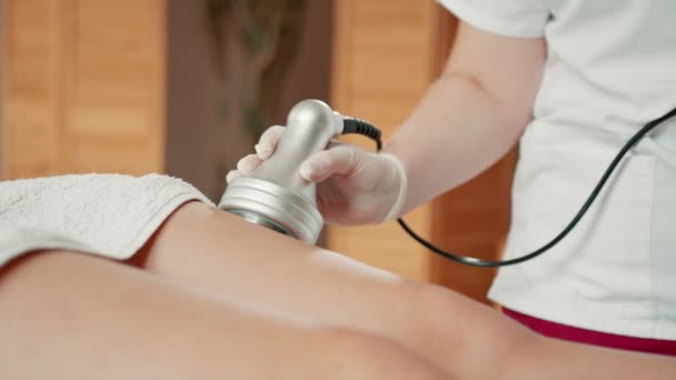Gebonden zicht op de professionele masseuse masserende voet van jong meisje met speciale apparatuur. Massagesalon concept — Stockvideo