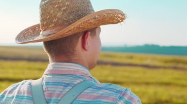 Erkek çiftçinin gün batımında mahsulü incelerken buğday tarlasına baktığı arka manzara. Kendine güvenen çiftçi tarlaya bakıyor.