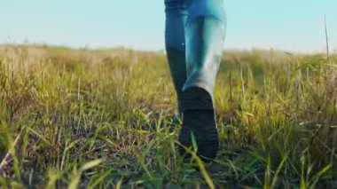Yeşil tarla boyunca lastik çizmelerle dolaşan tanınmayan bir çiftçi. İş için lastik botlar. Bir işçi yaz mevsiminde lastik çizme giyer. Tarım sektörü kavramı