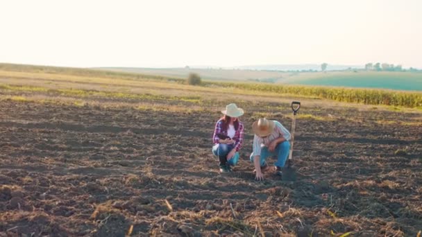 Přírodní organické zemědělství. Muž farmář se dotýká země na poli se svou kolegyní. Farmář drží a odlévá organickou půdu — Stock video