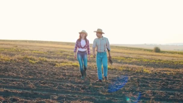 Twee boeren ingenieurs onderzoeken planten en veld tijdens het lopen en bespreken tijdens het kijken naar de camera. Begrip biologisch landbouwbedrijf — Stockvideo
