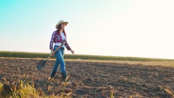 Vrouwelijke boer met een schop langs het veld met de grond. Vrouwelijke werknemer die in de zomer werkt. Begrip landbouwbedrijf en landbouw — Stockvideo