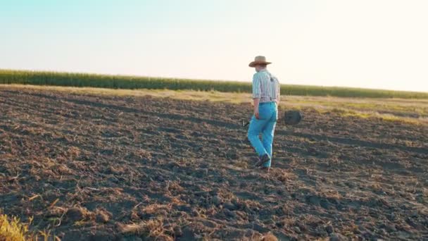 Boer gaat langs het veld met de grond. Mannelijke werknemer die in de zomer werkt. Begrip landbouwbedrijf en landbouw — Stockvideo
