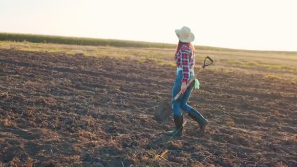 Kobieta rolnik z łopatą idzie wzdłuż pola z ziemi. Pracownica pracująca latem. Pojęcie działalności rolniczej i rolniczej — Wideo stockowe