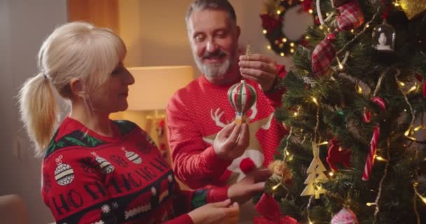밝은 백인 중년 부부와 남편 이 크리스마스 장난감 과 공을 집에 두고 크리스마스 트리를 장식하는 새해 파티를 준비하고 있다. 겨울 휴일 — 비디오