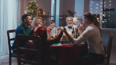 Evdeki Noel yemeğinden önce el ele tutuşup dua etmek. Güzel arkadaşlar yemek masasında oturuyor ve yeni yıl partisinde lezzetli yemekler yiyorlar..