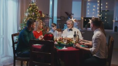 Sevgi dolu aile el ele tutuşup Noel yemeğinden önce evde dua etmeye başladı. Güzel arkadaşlar yemek masasında oturuyor ve yeni yıl partisinde lezzetli yemekler yiyorlar..