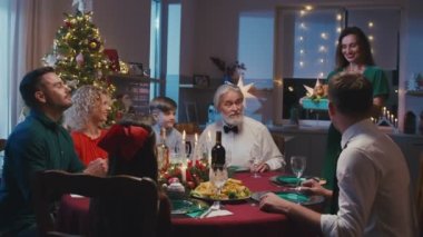 Büyük beyaz bir aile Noel 'i kutluyor, yemek masasında sohbet ediyorlar. Genç ve güzel bir kadın masaya kızarmış hindi getiriyor..