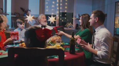 Büyük mutlu bir aile hediye alışverişi ve yemek masasında sohbet. Güzel arkadaşlar evde Noel yemeği veriyorlar..