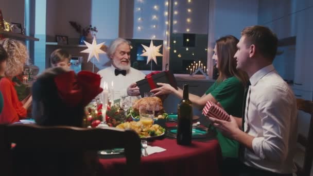 Büyük mutlu bir aile hediye alışverişi ve yemek masasında sohbet. Güzel arkadaşlar evde Noel yemeği veriyorlar.. — Stok video
