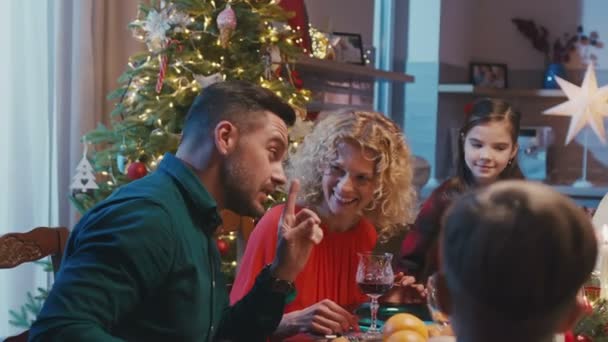 Família caucasiana feliz comemorando o Natal, conversando na mesa de jantar. Belos amigos que têm festa de Natal em casa, óculos de claque e fazer torradas. — Vídeo de Stock