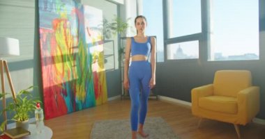 Kameralar, güneşli oturma odasında kameraya bakıp gülümseyen neşeli beyaz kadın sporculara yaklaşıyor. Mutlu, formda, yüzünde gülümseme olan bir kadına yaklaş. Spor tarzı konsepti